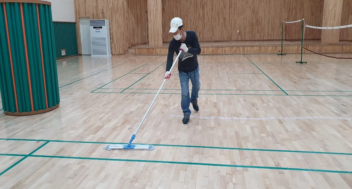 강당 바닥을 닦는 작업자